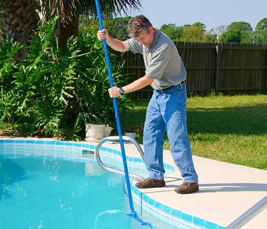 Professional pool maintenance technician using skimmer net for weekly pool cleaning and debris removal
